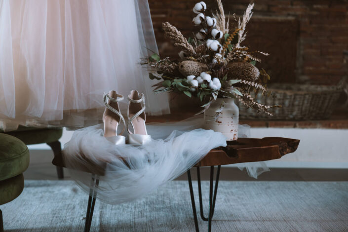Nahaufnahme von den Brautschuhen und dem Schleier auf einem dekorativen Holztisch