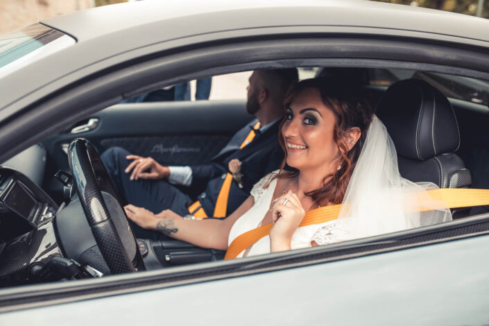 Das Brautpaar ist durch das Autofenster zu sehen, lachend und verliebt, fotografiert von Roder Photography