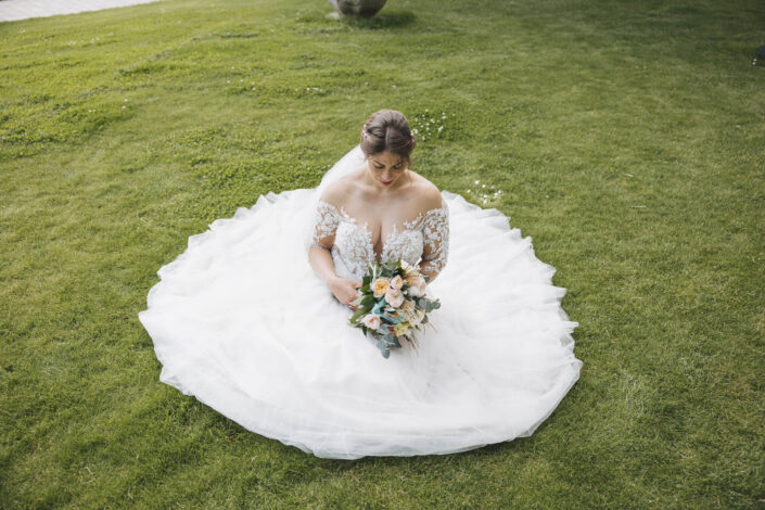 Die Braut sitzt auf dem Boden, ihr Hochzeitskleid ist rund um sie ausgebreitet – fotografiert von Christian Roder