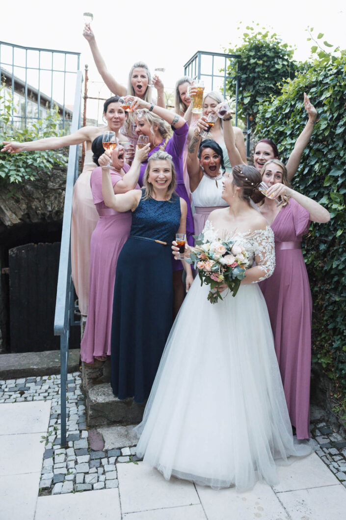 Die Braut steht lachend mit ihren Freundinnen am Hochzeitstag zusammen – fotografiert von Christian Roder